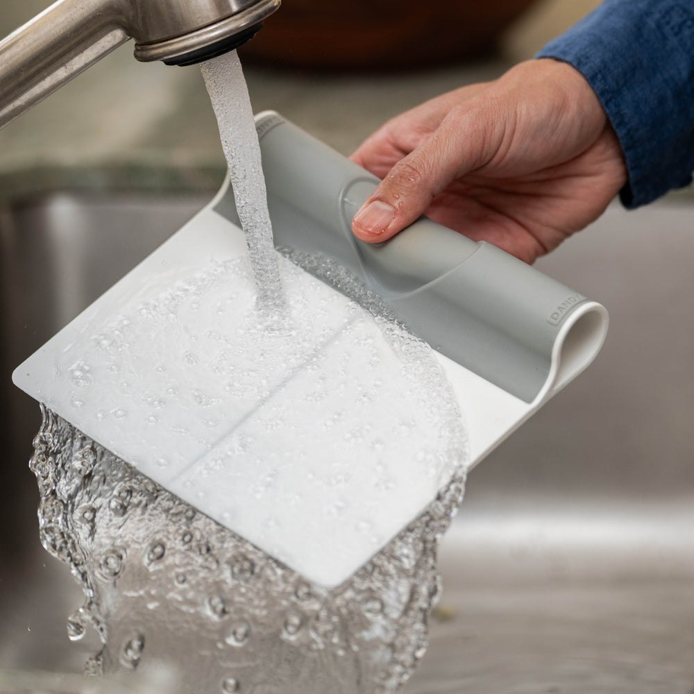 Hand washing the gray and white folding food scooper