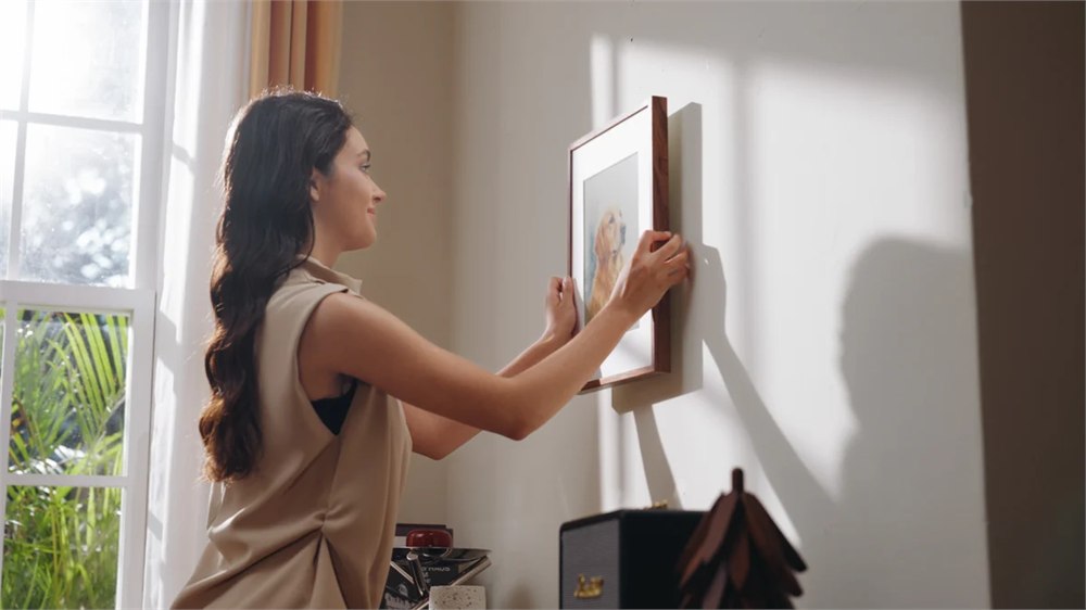 Woman adjusting a wall-mounted Jitrainno art frame