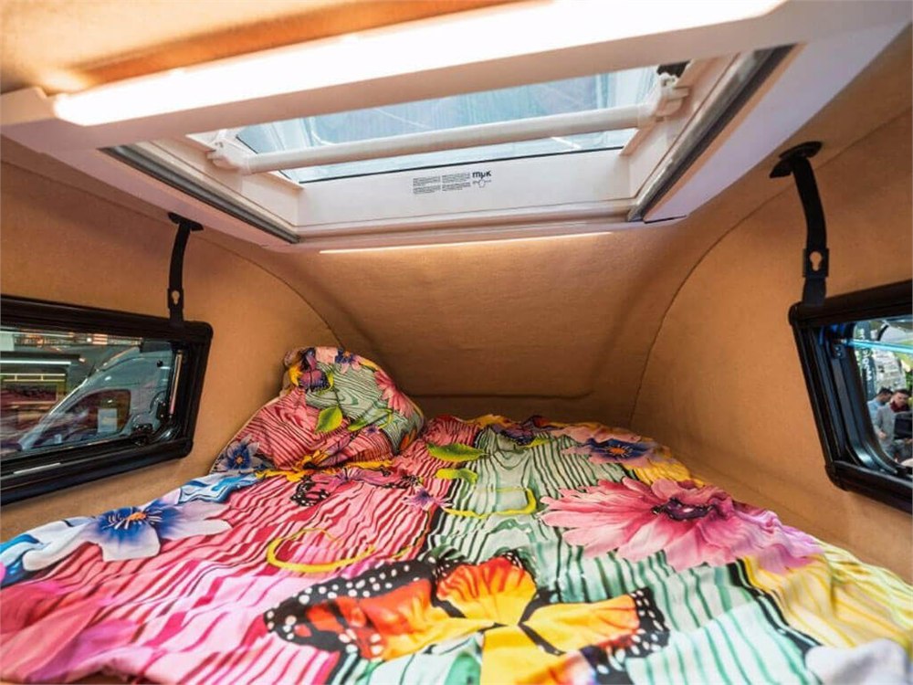 Upper sleeping area with side windows and a roof hatch in the display camper
