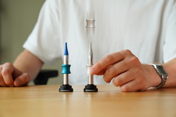 Blue and silver MEZMODROP desk toys being demonstrated