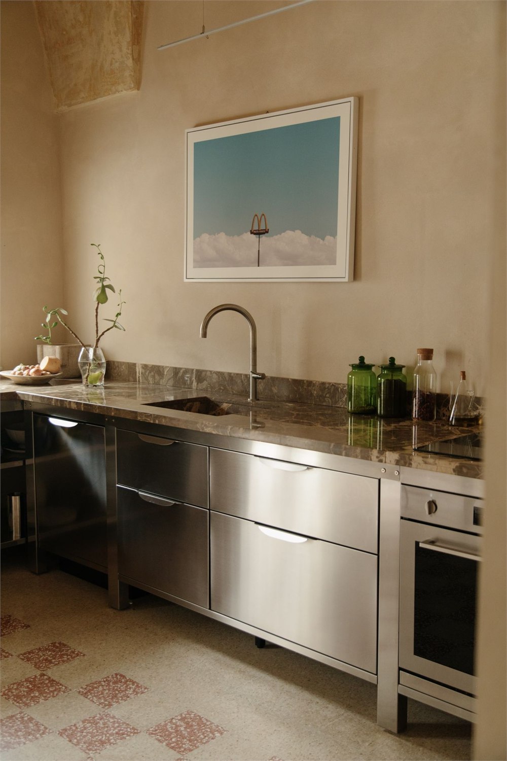 Stainless steel kitchen modules installed in a room with patterned tile flooring