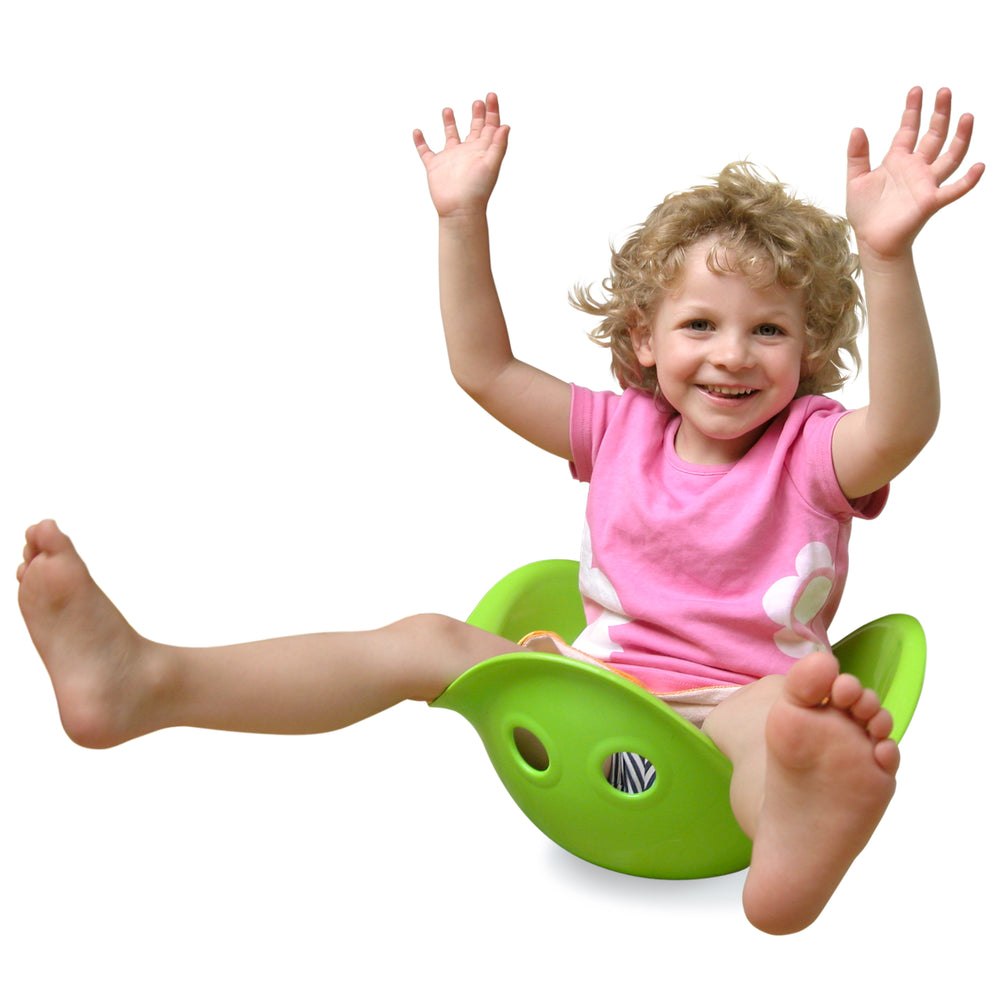 Child sitting and balancing in a green MOLUK Bilibo spinning shell toy.