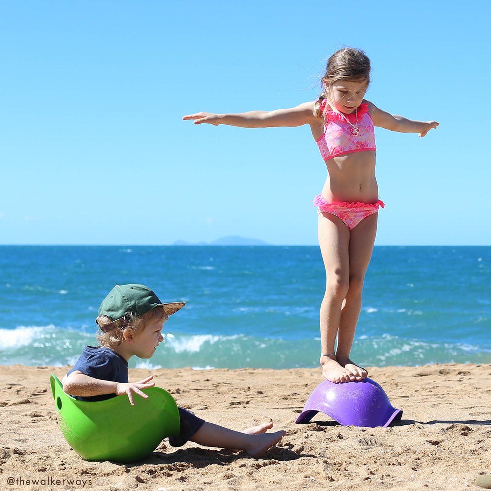 Purple and green MOLUK Bilibo shells used for beach and sand play.
