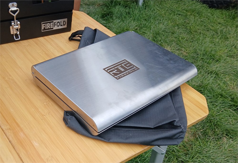Folded FireFold stainless fire pit beside its carry bag