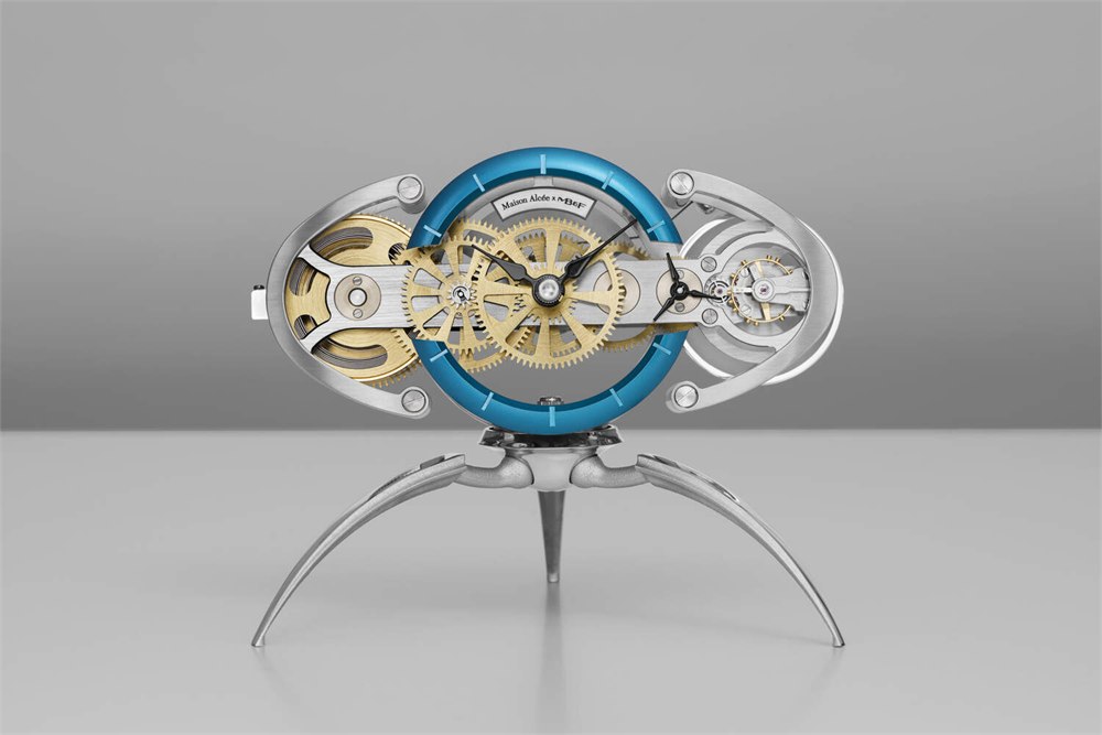 Nostromo mechanical desk clock front view with blue dial and exposed brass gears