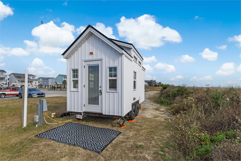 Petite Pelican 16-foot tiny house with white board-and-batten siding on a trailer