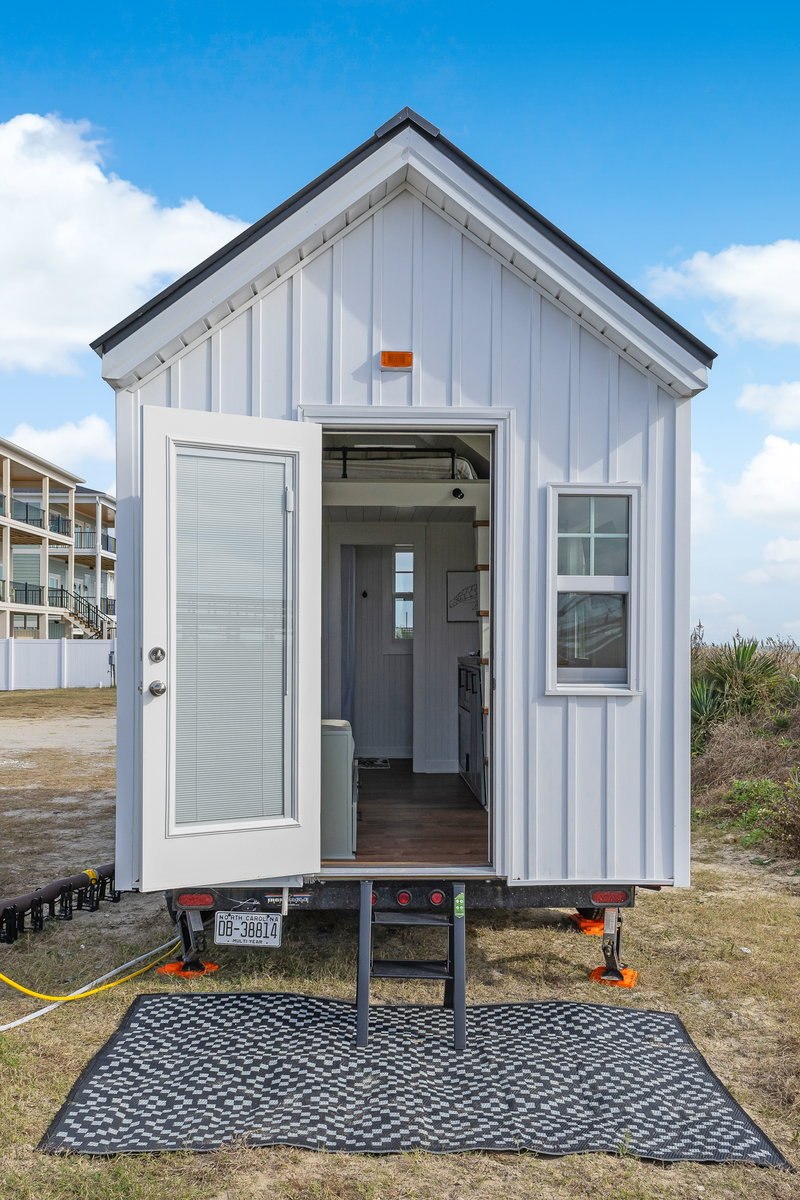 Petite Pelican tiny house exterior showing white siding and black metal roof