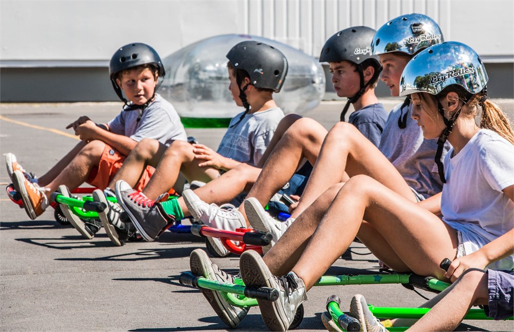 Helmeted children seated on EzyRoller ride-ons in several colors
