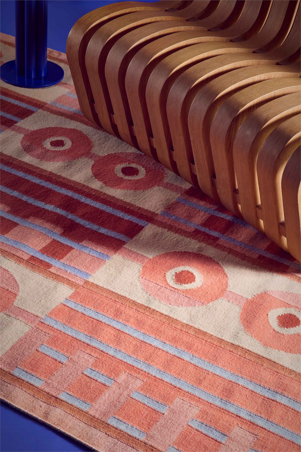 Tangerine rug styled beside sculptural wooden seating