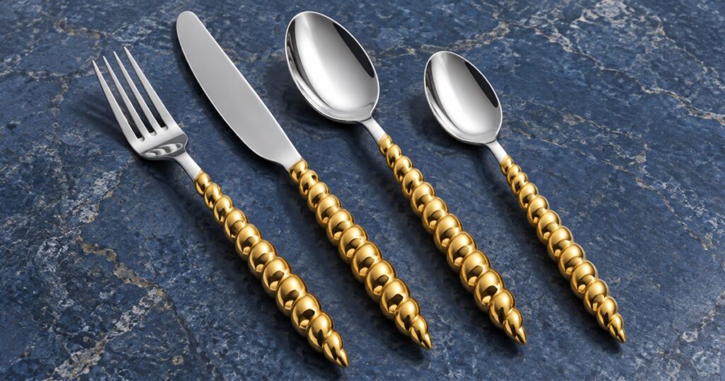 Four-piece shell-handle gold flatware on a blue surface