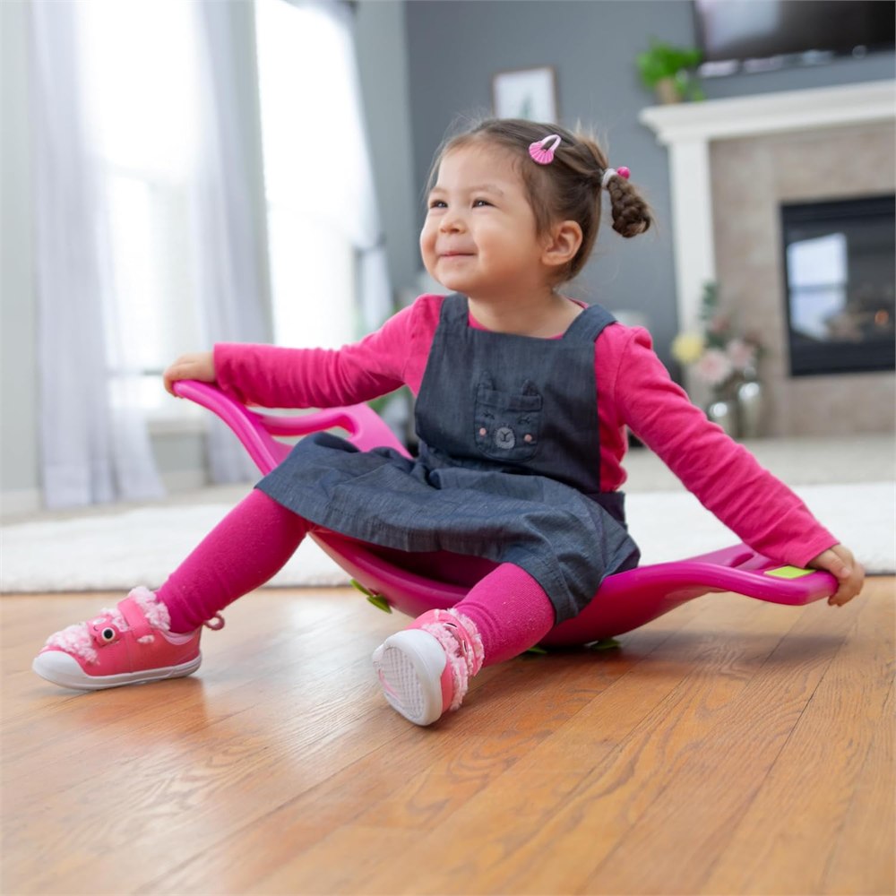 Child seated in a pink Teeter Popper holding both handles