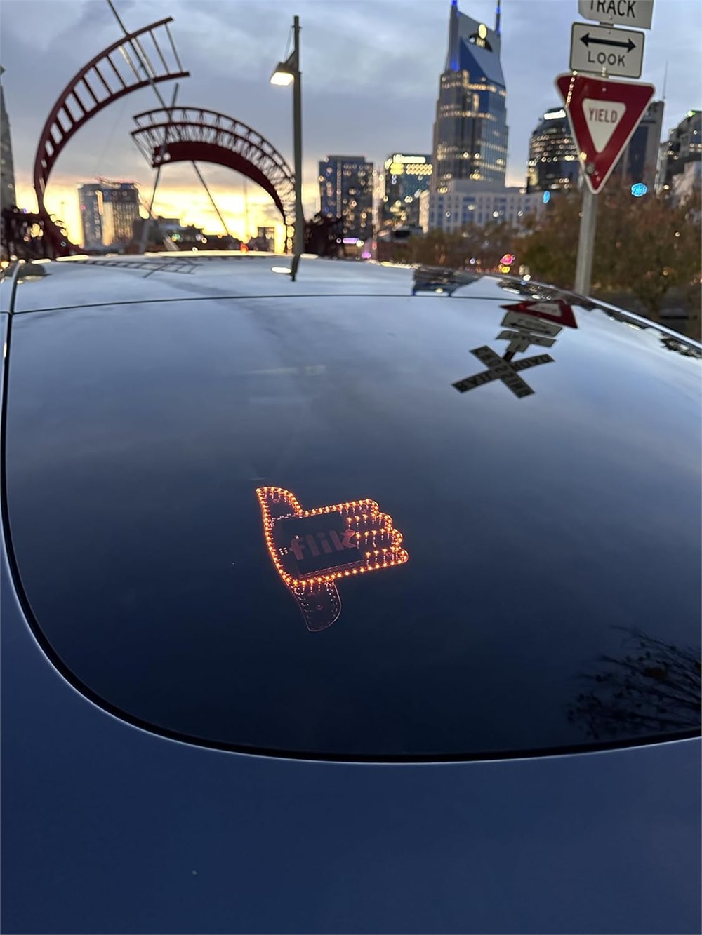 Amber thumbs-up light visible through a car rear window
