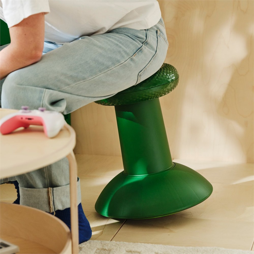 Person sitting on the green IKEA x Xbox YXSTABY thumbstick stool beside a gaming table