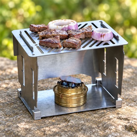 FlameMage titanium camping stove with grilled food and a brass alcohol burner