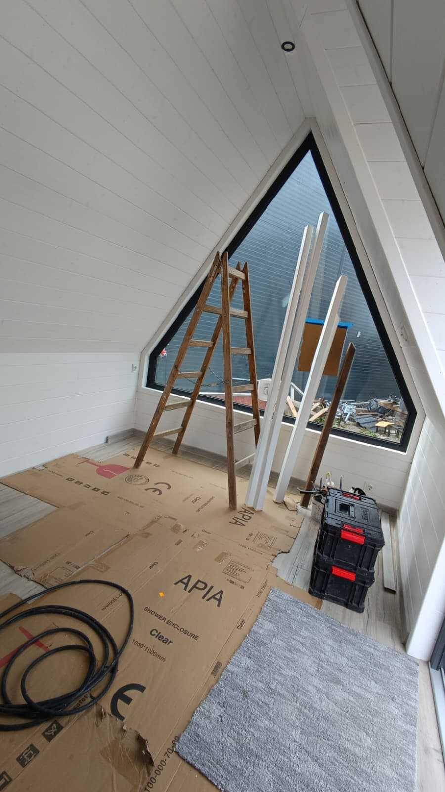 White wood-lined main room with triangular glazing during construction