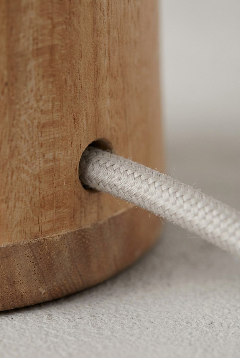 Beige fabric cable emerging from the oak lamp body