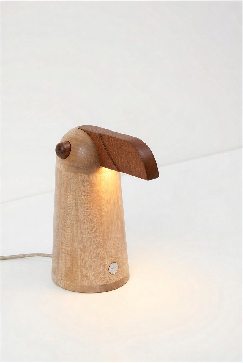 TUPI oak bird lamp illuminated beneath its dark wooden beak