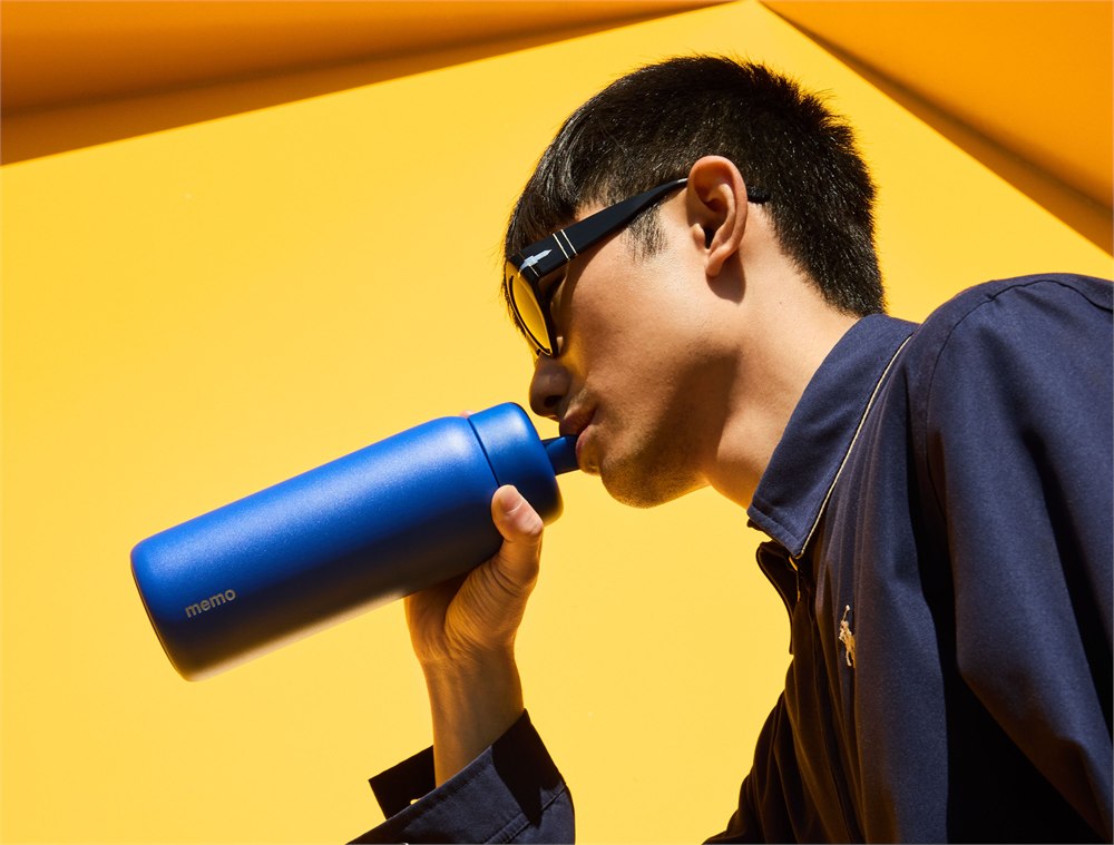 Person drinking from a blue memo ROUND bottle