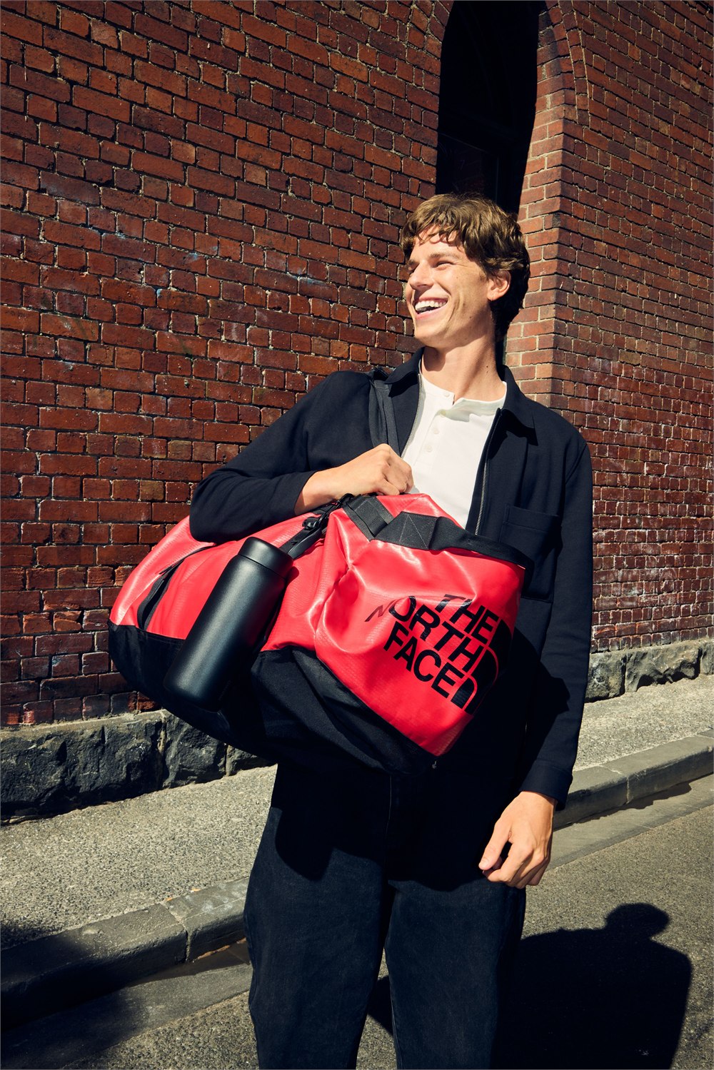 Black memo ROUND bottle attached to a red travel bag