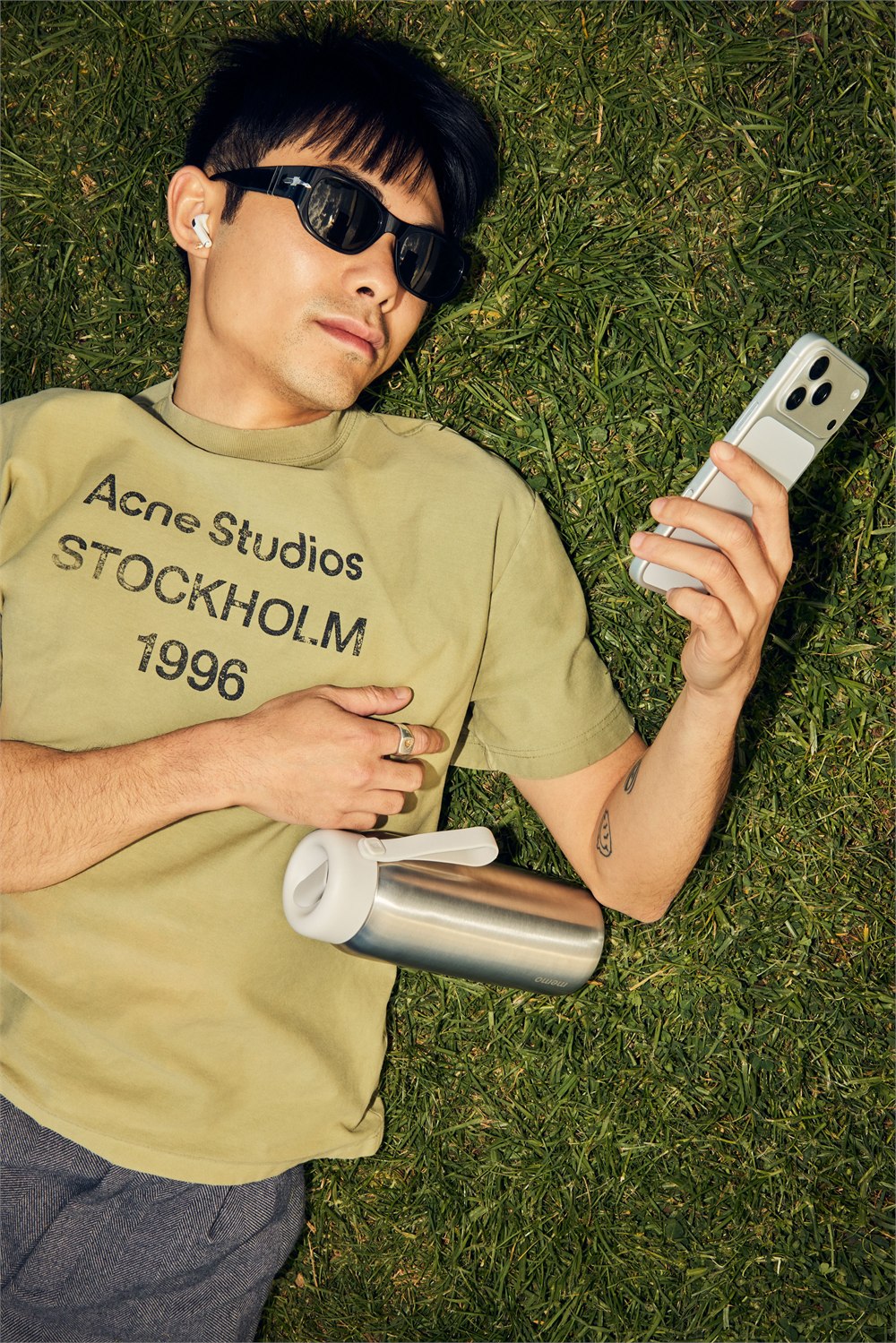 Person resting on grass with a silver memo ROUND bottle