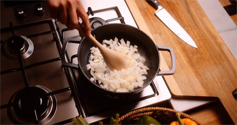Onions being stirred in the FIREUP braiser on a gas stovetop