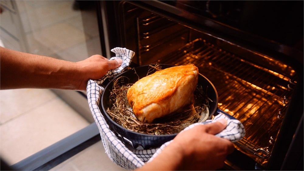 FIREUP braiser being moved into an oven with chicken inside