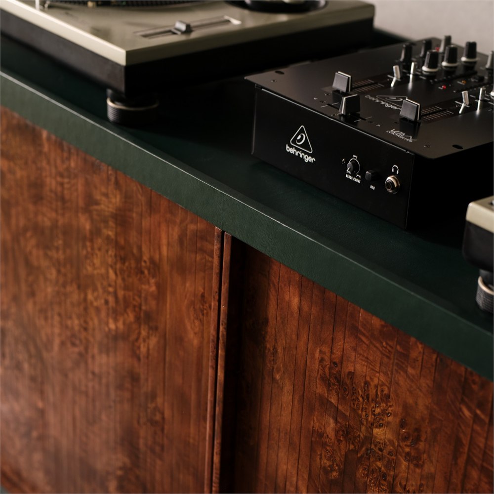 Turntable and mixer resting on the green leather top above the burl wood doors