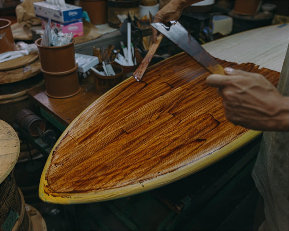 Urushi lacquer being applied to a wooden surfboard