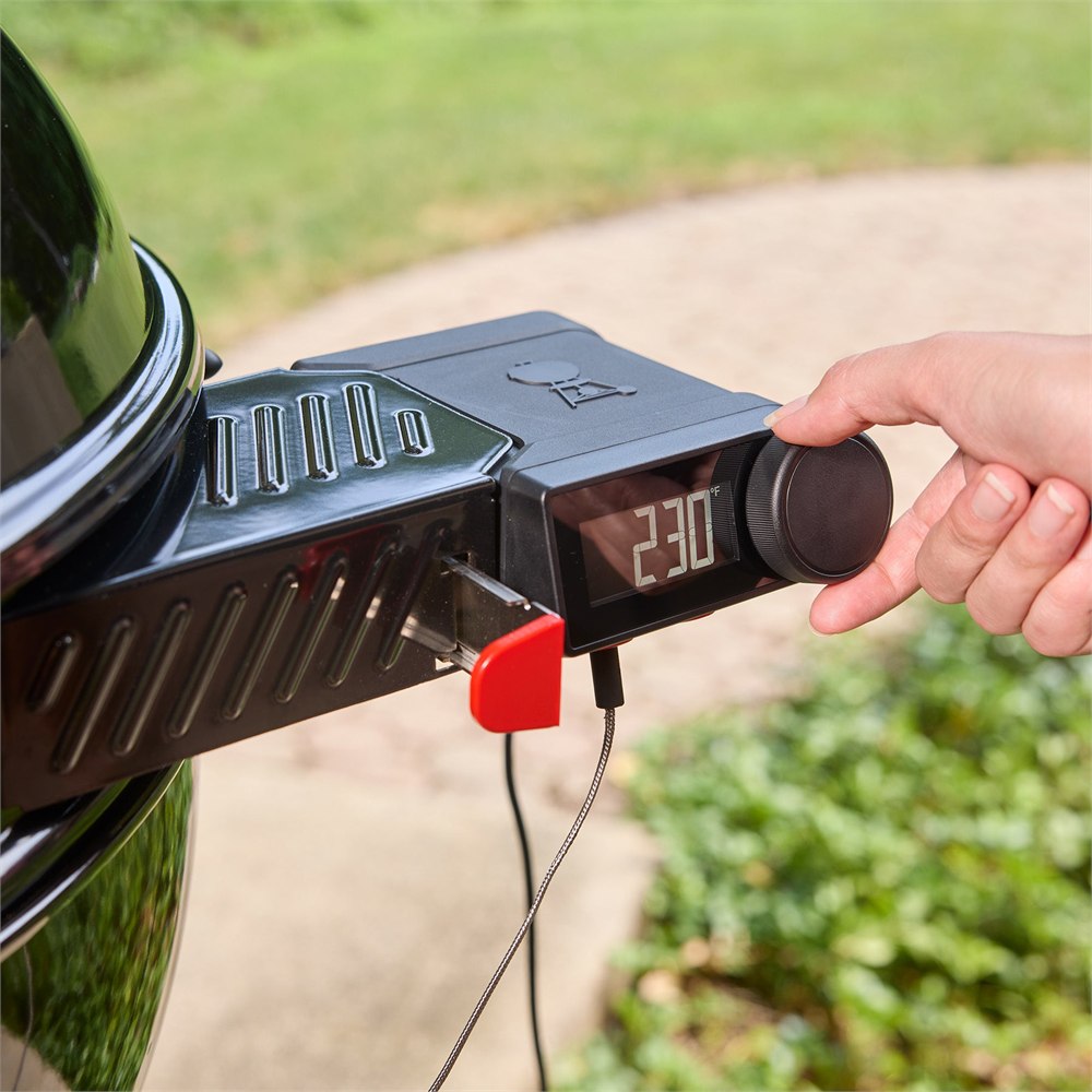 Hand adjusting the temperature controller on the kettle ring