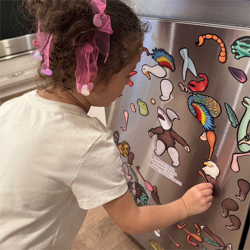 Child arranging magnetic creature parts on a fridge