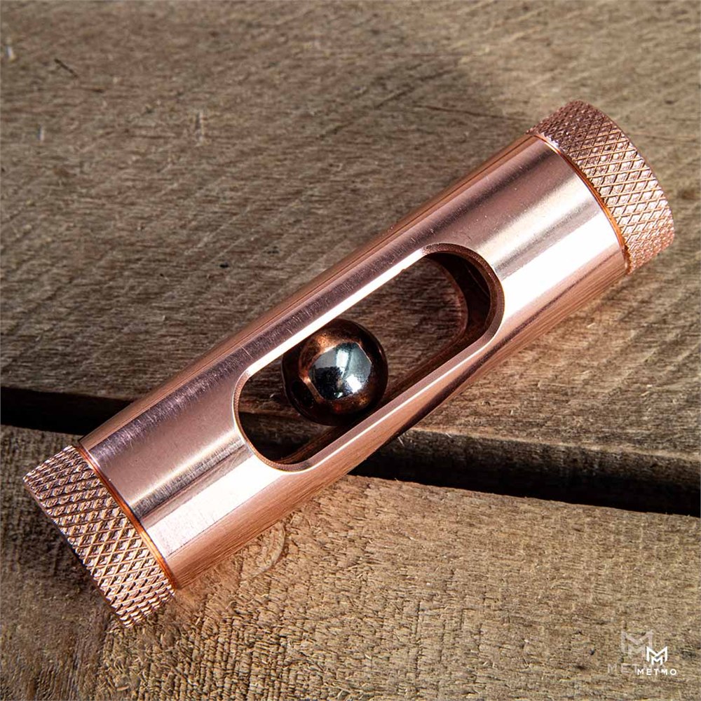 Copper Eddy tube lying diagonally on wood with a reflective magnet inside