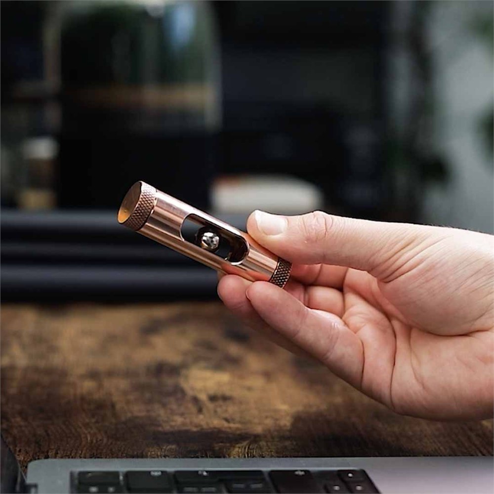 MetMo Eddy copper magnetic desk toy held in one hand above a desk