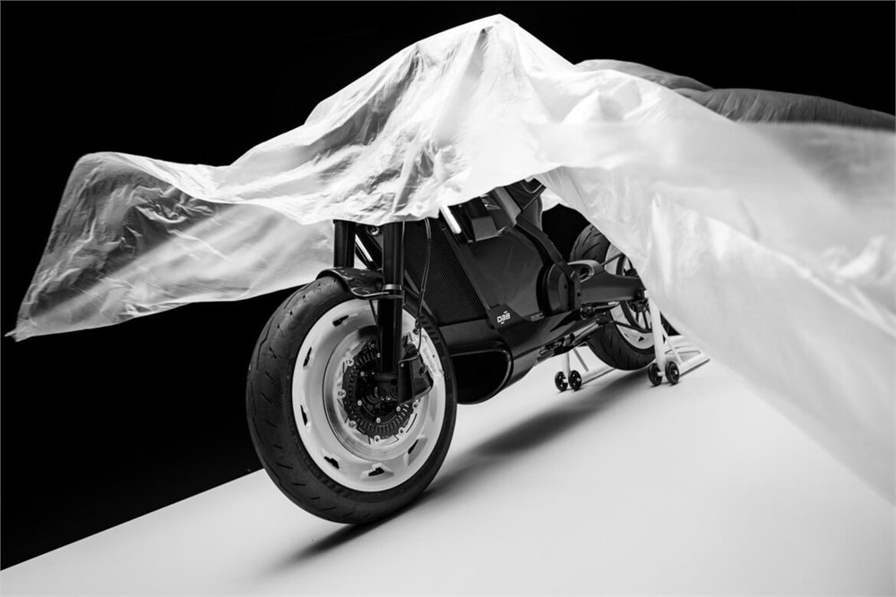 Front wheel and body of the electric motorcycle beneath an unveiling cloth