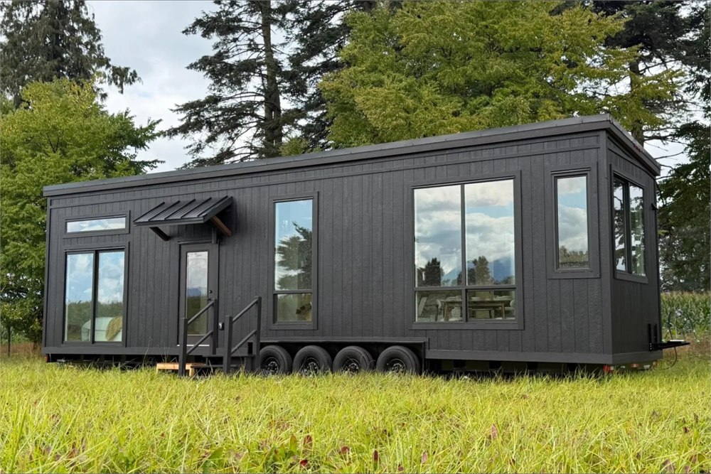 Mint Ventura tiny house with dark siding, tall windows and four trailer axles
