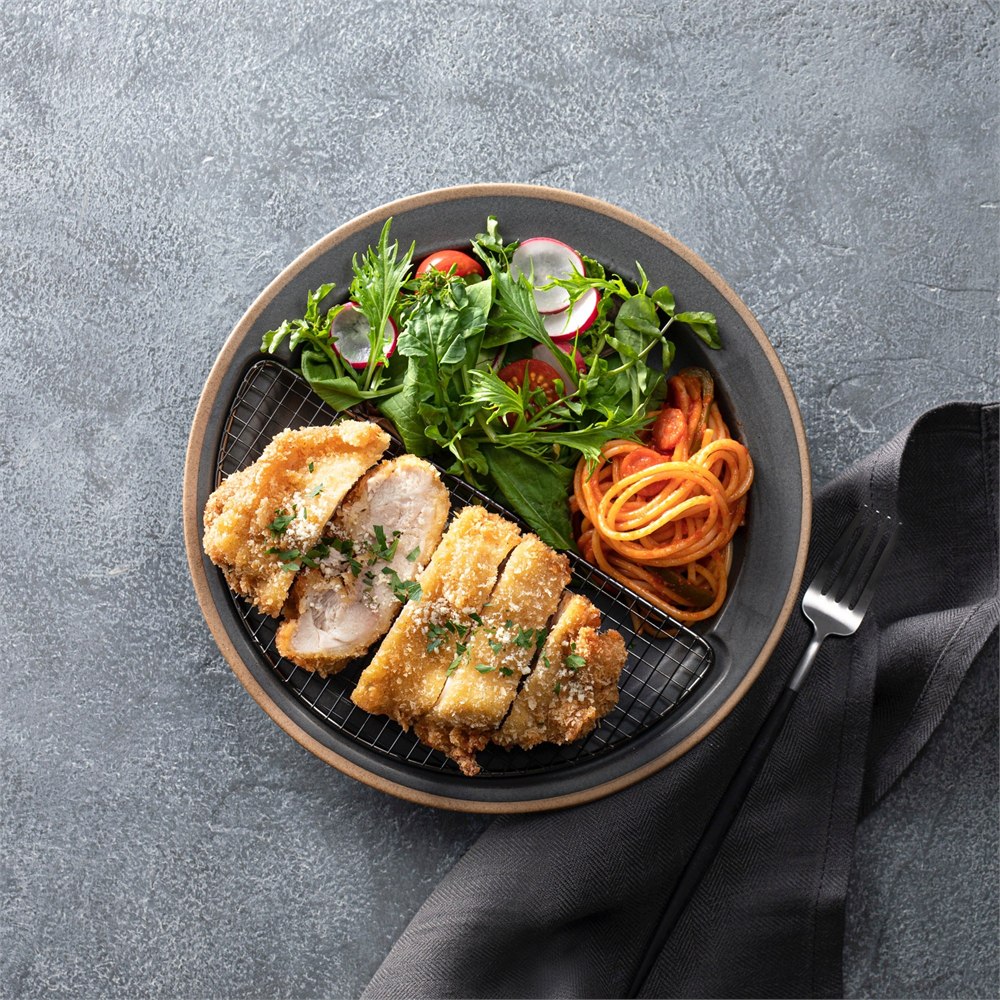 Overhead view of a black Half-Moon Plate with sliced chicken and vegetables