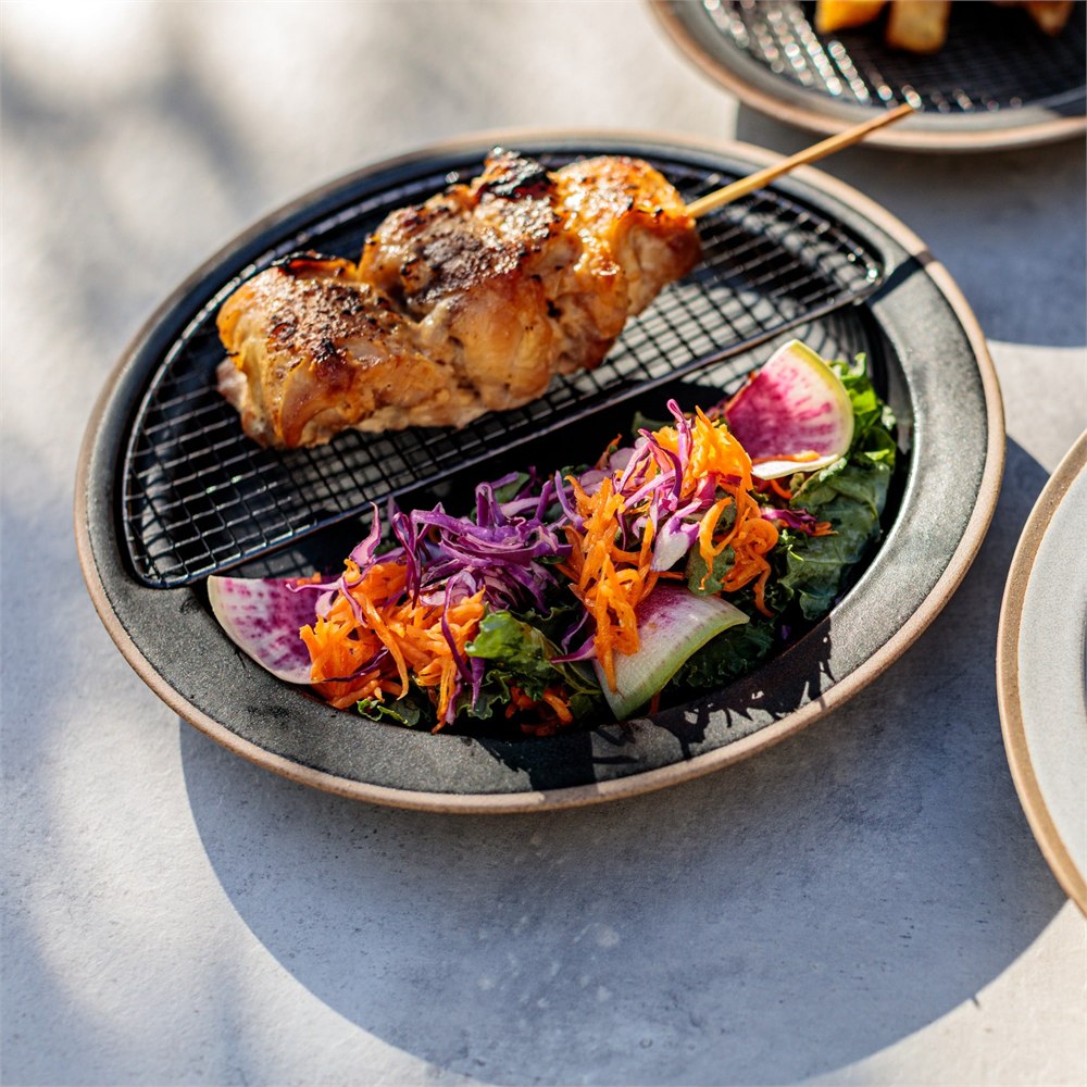 Grilled food served on the half-circle rack beside a colorful salad