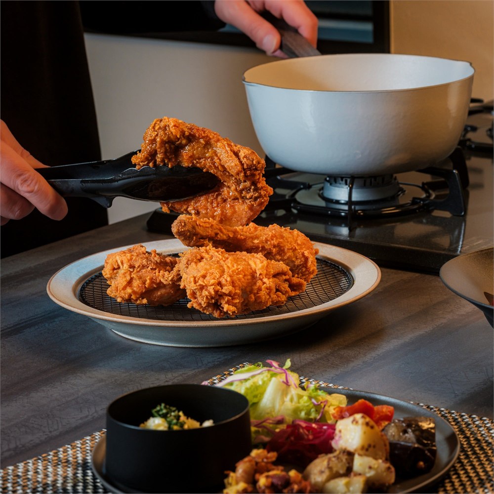 Freshly fried chicken being placed onto the plate beside the stove