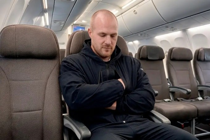 Traveler resting crossed forearms in the STR-8 Jacket 2.0 support pocket on an airplane