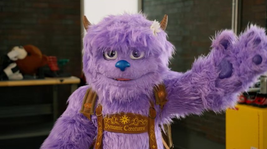 Hugo waving a purple padded paw