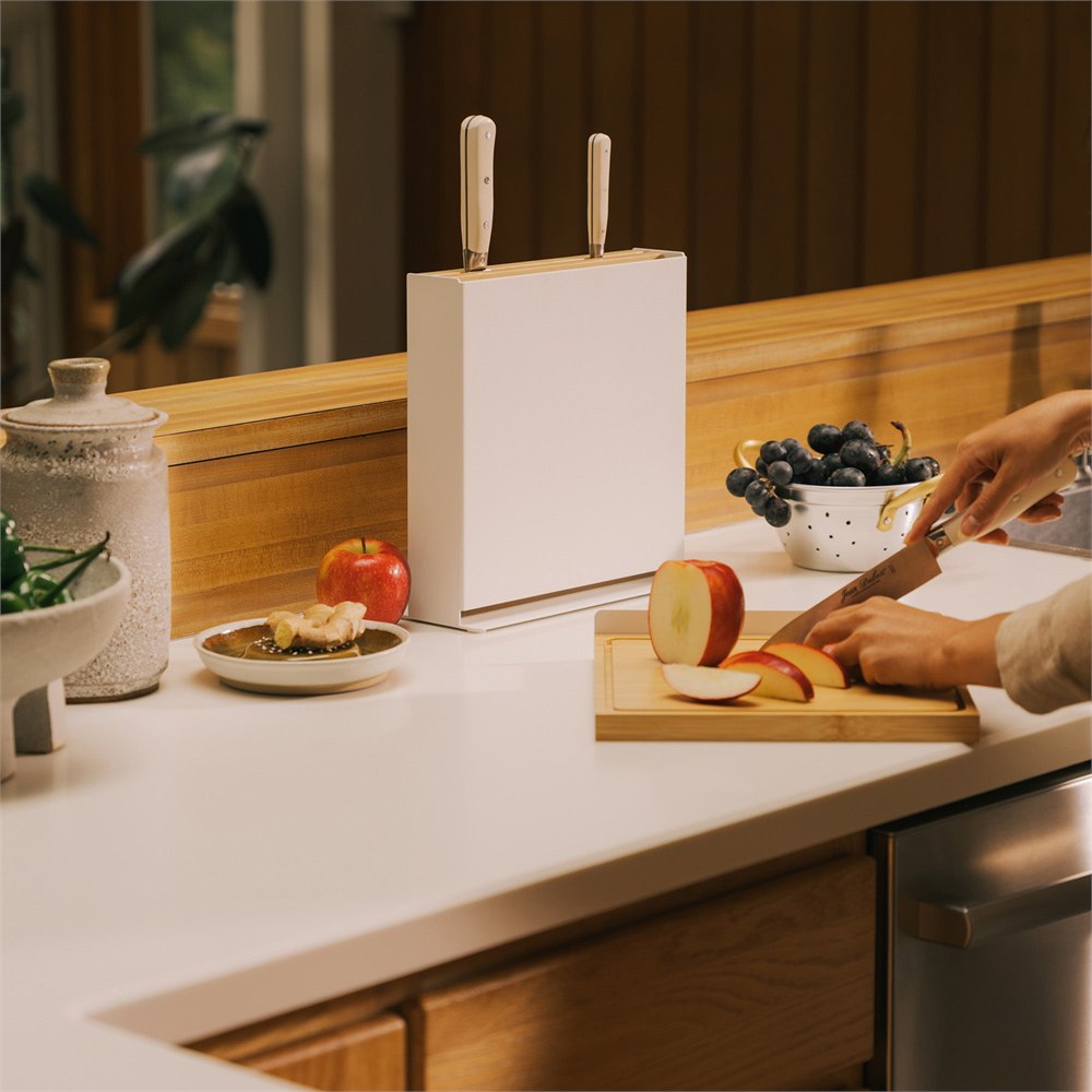 Cutting an apple on the removable board beside the knife stand