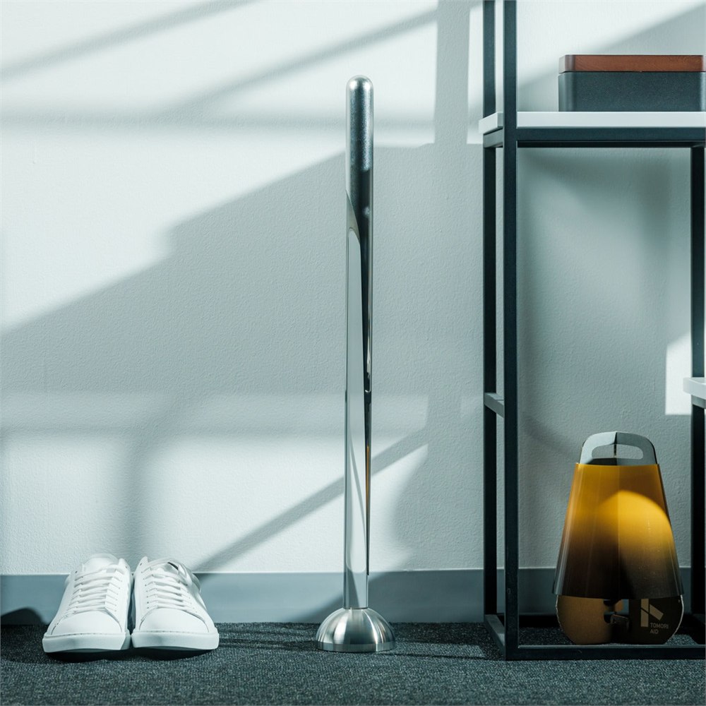 Invisible Shoehorn in its clear stand beside a pair of shoes