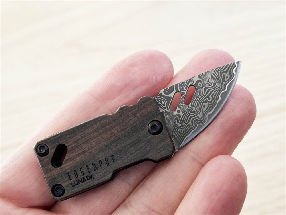 Edge & Pop folding Damascus pocket knife held between fingers to show its compact size.