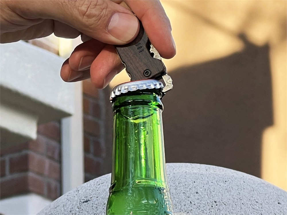 Edge & Pop knife opening a beer bottle, showing the built-in bottle opener.