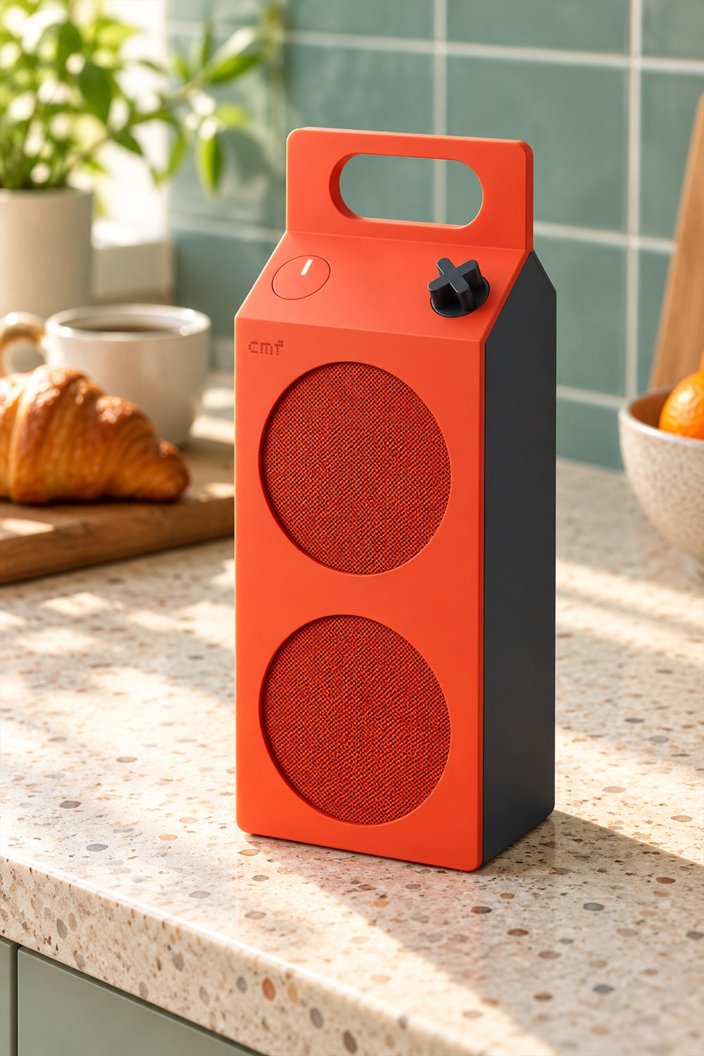 AI-generated kitchen view of an orange CMF Speaker M with two circular grilles, an integrated carry handle and a black X-shaped knob on a terrazzo counter beside breakfast.