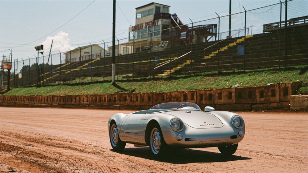 Silver Porsche 550 J parked beside a motorsport grandstand