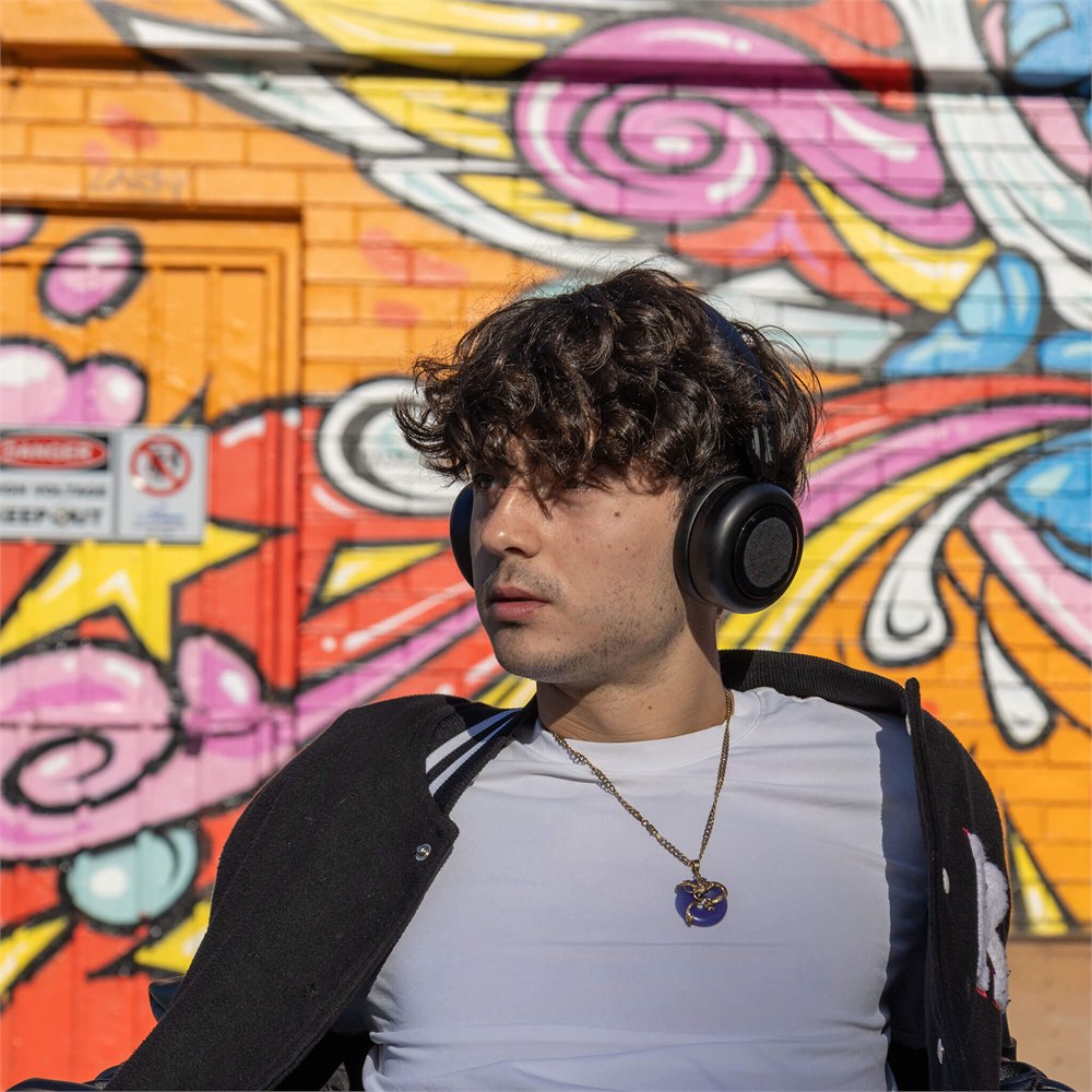 Listener wearing black TDM Neo headphones in front of a colorful wall