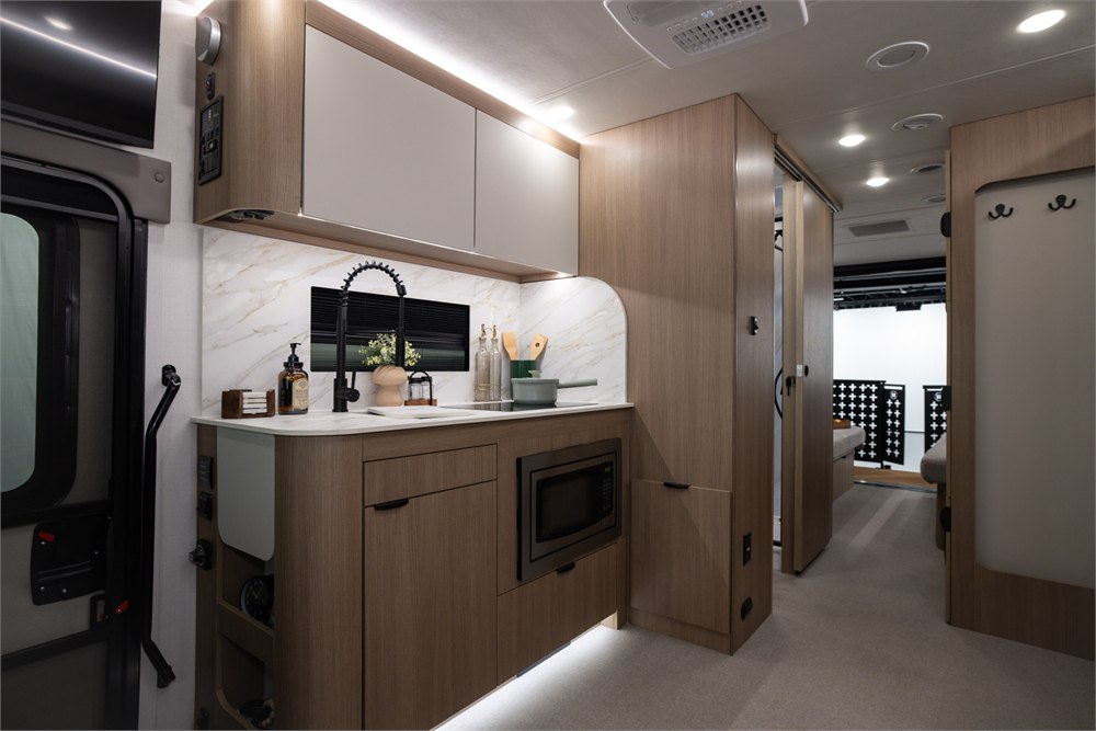Motorhome kitchen with wood-tone cabinetry and a black faucet