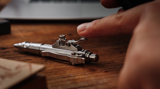 Finger pressing the small telegraph-style lever on the stainless-steel pen
