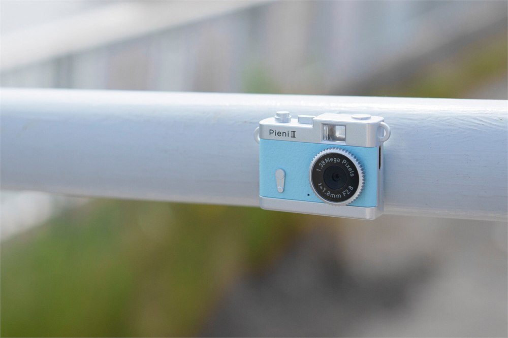 Blue Pieni III camera attached magnetically to a metal railing
