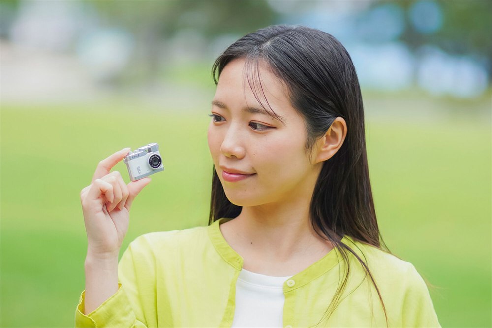 Woman holding the tiny Pieni III camera between her fingers
